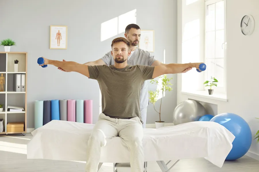 Ung mann som mottar veiledning fra fysioterapeut som del av rehabiliteringsprogram