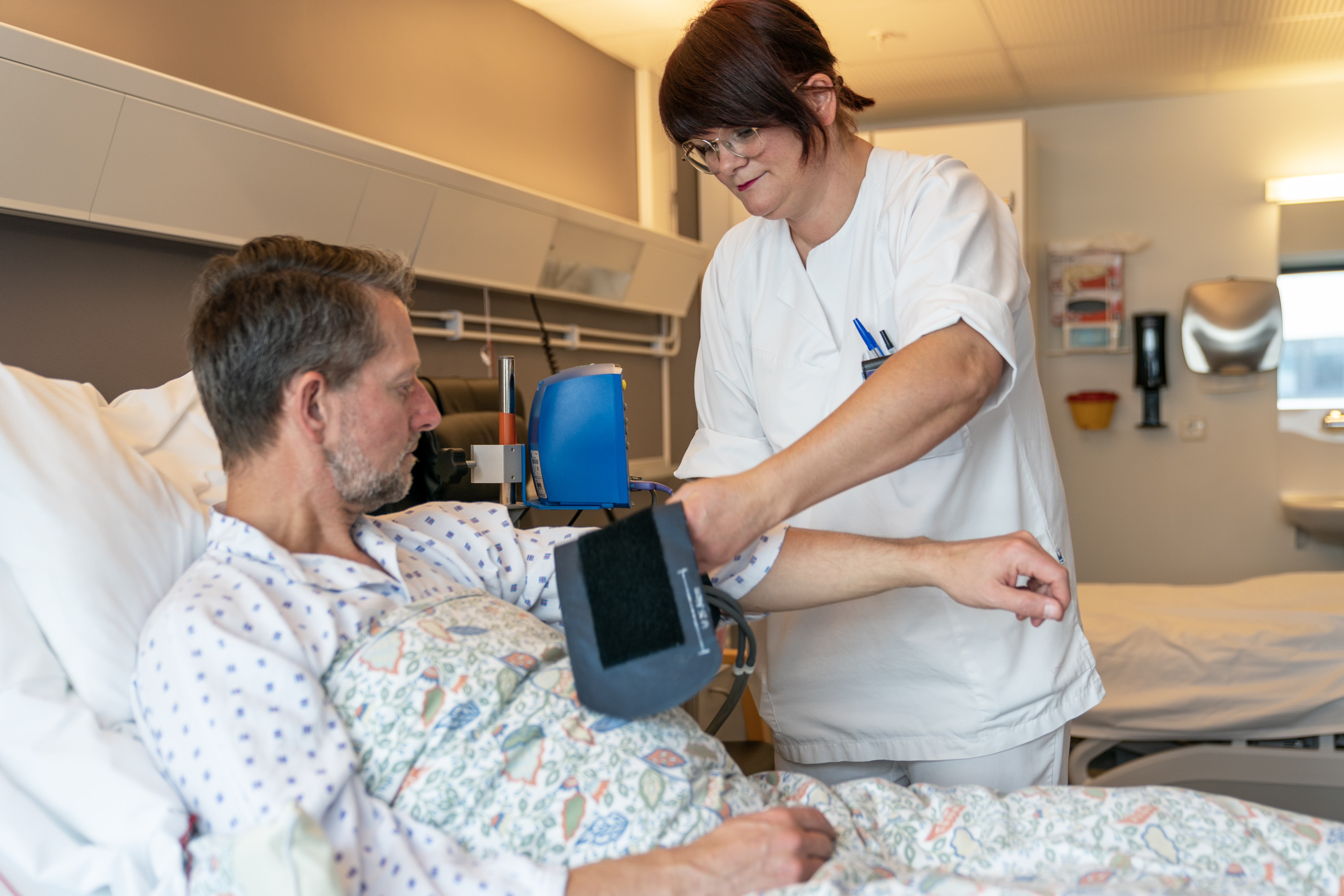 Sengepasient får hjelp fra sykepleier