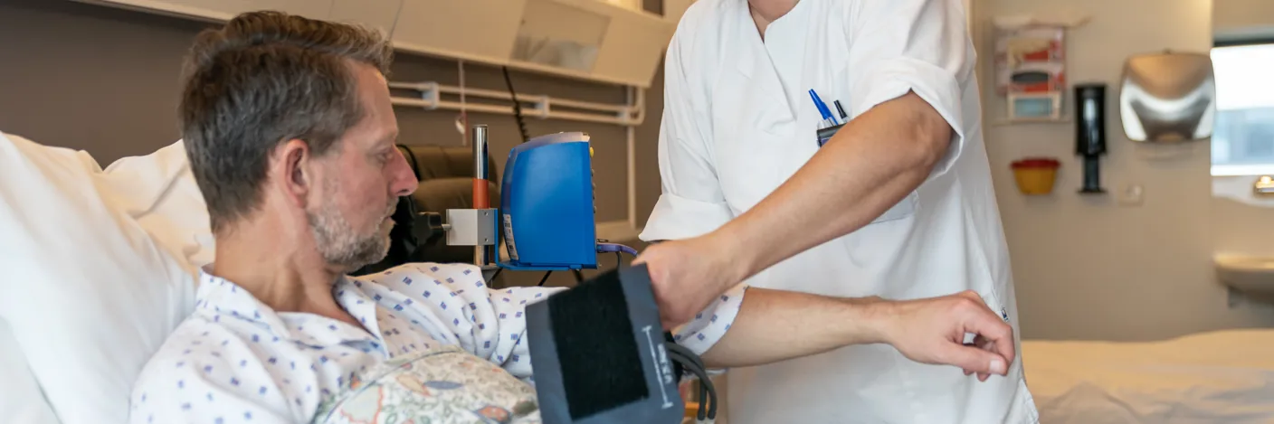 Sengepasient får hjelp fra sykepleier